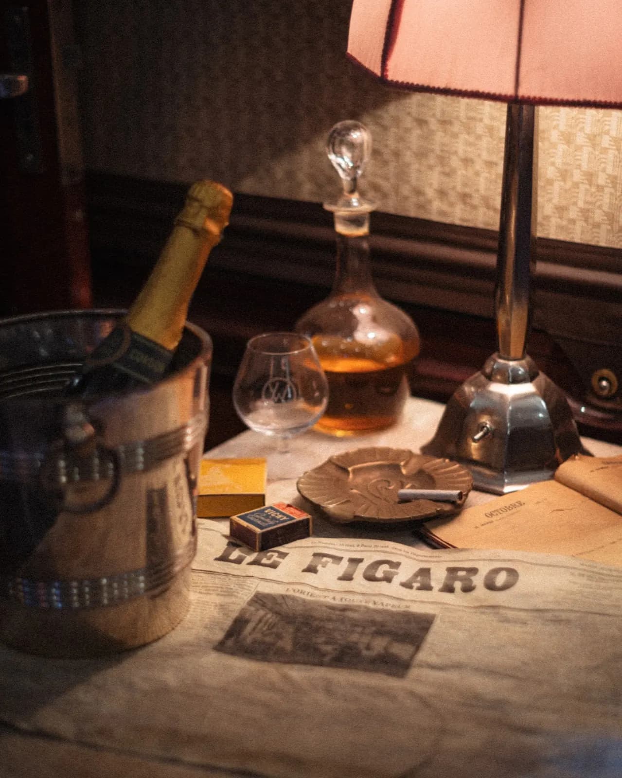 Still life on a train table - decanter, glass and a folded copy of Le Figaro